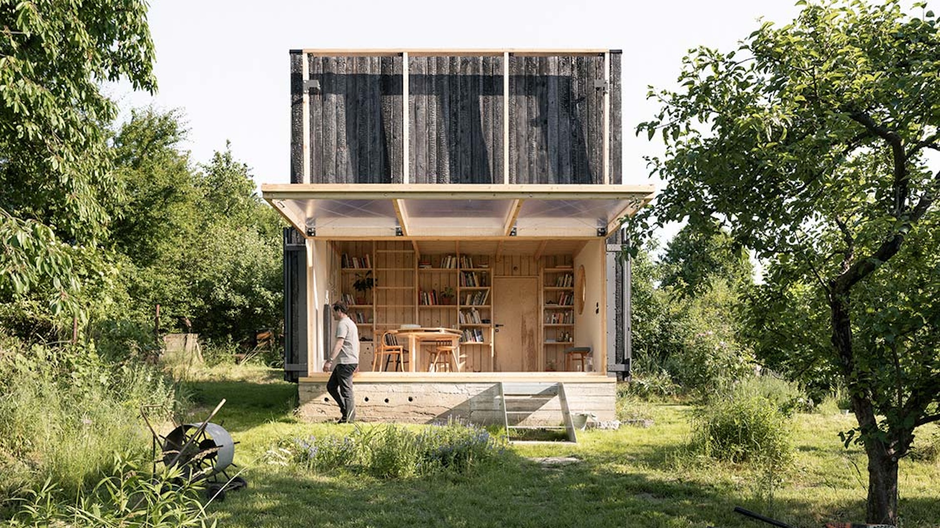 Bahçeli ev projesi üzerinde çalışan mimarlık ekibi; masa üzerinde plan çizimleri, cephe eskizleri, peyzaj notları ve bilgisayar yer alıyor.