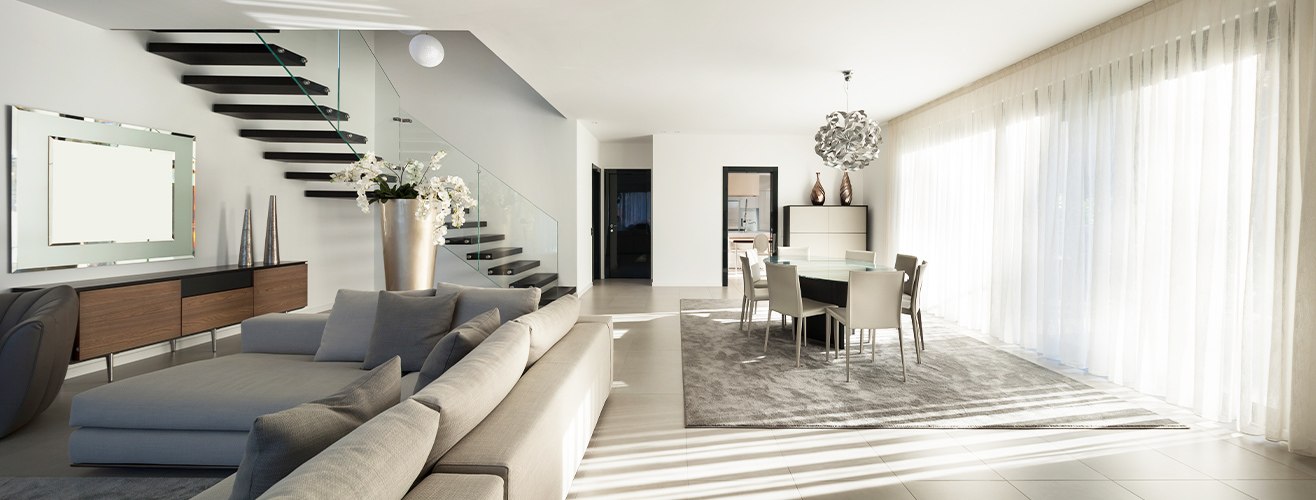 Lüks villa tasarımı üzerinde çalışan mimarlık ekibi; masa üzerinde plan çizimleri, cephe eskizleri, malzeme örnekleri ve bilgisayar yer alıyor.