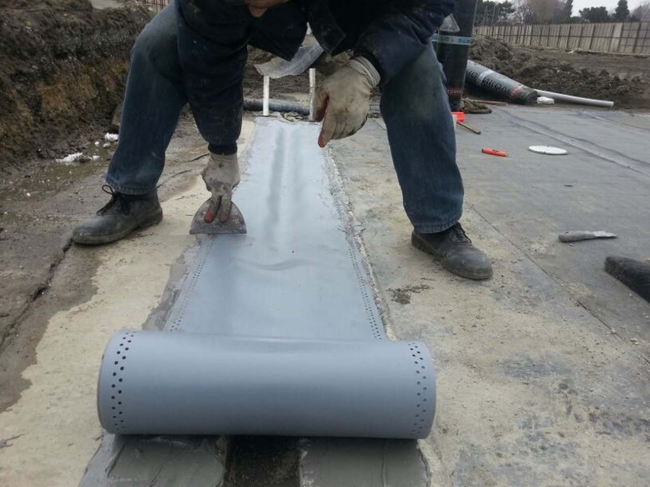 Geniş ve uzun bir betonarme yapıda, binayı iki bağımsız bloğa ayıran ve üzeri esnek metal bir profille kapatılmış yapısal dilatasyon boşluğunun yakından görünümü.