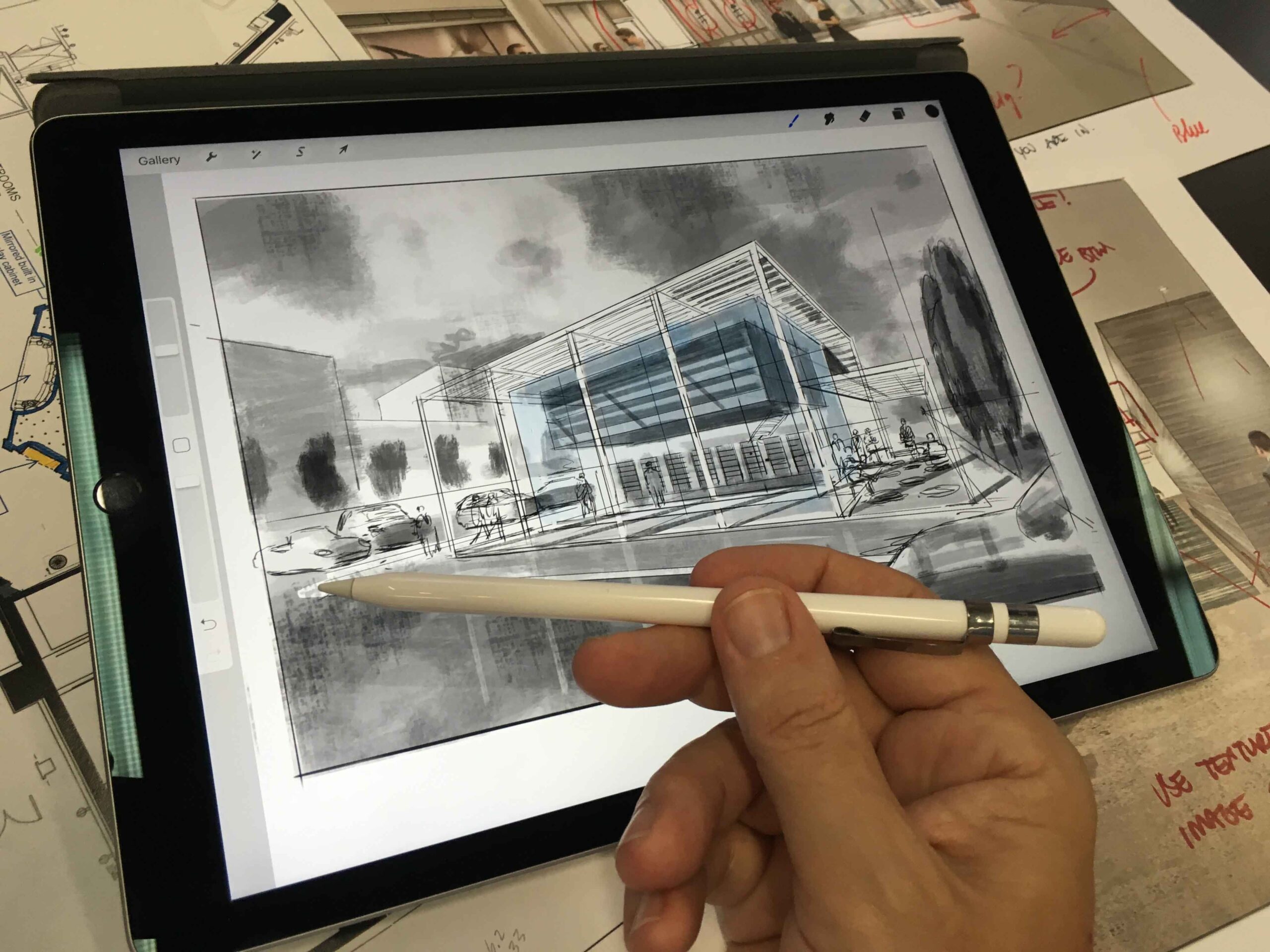 Bir mimarın masasında duran iPad ekranında, Apple Pencil ile çizilmiş ölçekli bir mimari kat planı ve hemen yanında binanın perspektif eskizi; arka planda ise el yazısı notlar ve tasarım katmanları görünmekte.